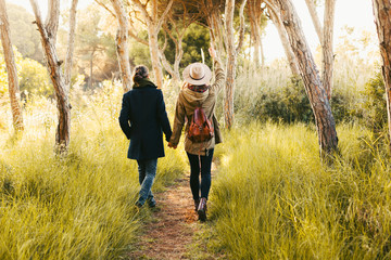 Back view of a hipster couple walking in the forest.