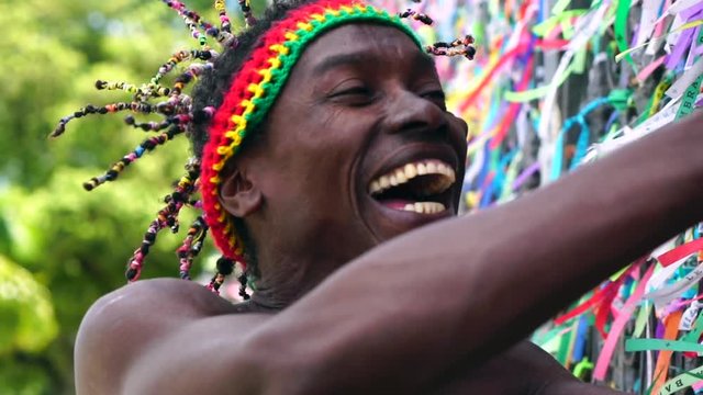 Brazilian making a wish with brazilian ribbons (Fita do Bonfim) on church fence in Salvador, Bahia, Brazil