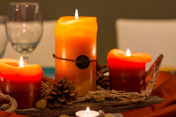 Rustic orange and red glowing candle and pinecone centerpiece on reclaimed wood