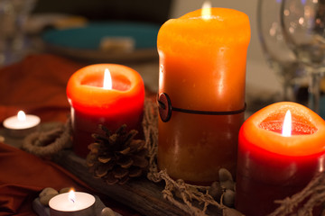Rustic orange and red glowing candle and pinecone centerpiece on reclaimed wood