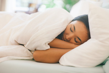 Side view of a young asian woman sleeping in white bed.