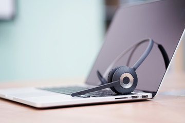 close up soft focus wireless headphone call centre hotline at computer office desk background concept.