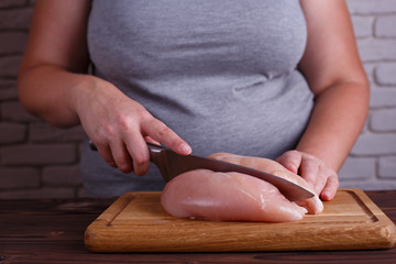 Overweight woman hands chopping up chicken breasts . Dieting, healthy low calorie food, weight losing concept, low carb diet