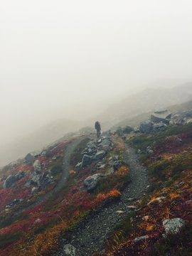 Solo Hiker Climbing Winding Mountain Path Through The Fog