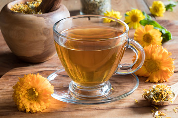 Calendula tea with calendula flowers on a wooden table