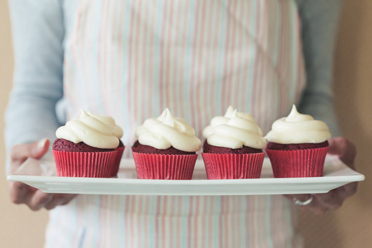 Woman holding a plate of red velvet cupcakes