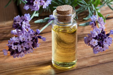 Obraz na płótnie Canvas A bottle of lavender essential oil on a wooden background