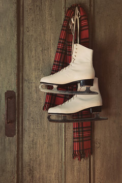 Ice skates with plaid scarf hanging on door