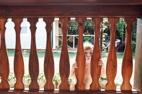 Little girl behind a wooden fence of porch