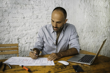 Senior designer working at laptop and sketches