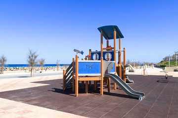 Fototapeta na wymiar Children's safe wooden playground recreation area at seaside public park