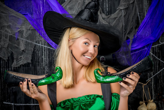 beautiful witch in a hat with green halloween shoes
