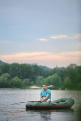 Foto op Canvas Man fishing from inflatable boat on river © Africa Studio
