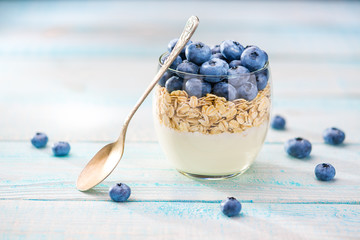 Yogurt with muesli and blueberries on a wooden table.