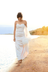 Fototapeta na wymiar Beautiful bride walking on beach