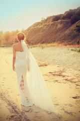 Fototapeta na wymiar Beautiful bride walking on beach