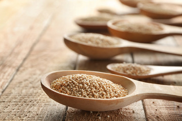 Spoons with quinoa seeds on wooden table