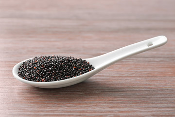 Spoon with quinoa seeds on wooden table