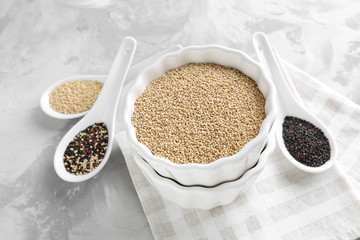 Bowl and spoons with different quinoa seeds on table