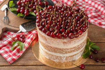 Delicious cake decorated with cherries on table
