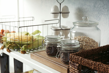 Jars of coffee beans and cereal on shelf indoors