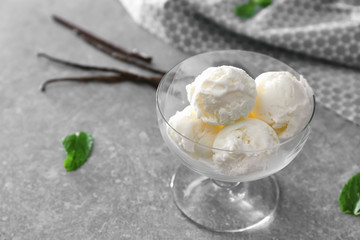 Glass bowl with yummy vanilla ice cream on table