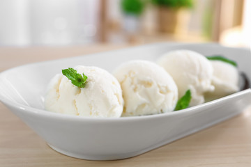 Dish with yummy vanilla ice cream balls on wooden table