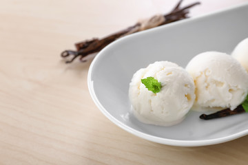 Dish with yummy vanilla ice cream balls on wooden table
