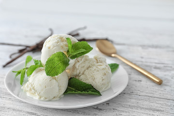 Plate with yummy vanilla ice cream on wooden table