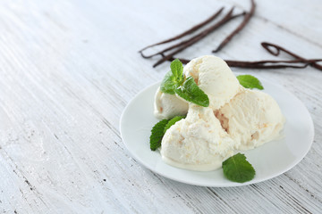 Plate with yummy vanilla ice cream on wooden table