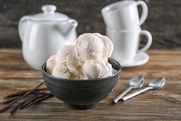 Bowl with yummy vanilla ice cream balls on wooden table