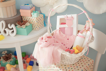 Fototapeta na wymiar Wicker basket with gifts for baby shower indoors
