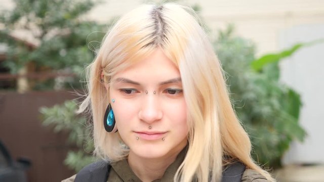 bodimodification, portrait of a girl with face piercings and tunnels in the ears. 4k, slow-motion shooting, copy space