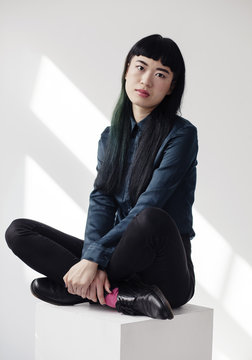 Portrait of a cool young fashionable woman on a white cube