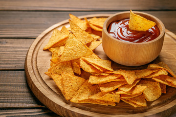 Mexican nachos chips with a sharp tomato sauce on the tray. Concept - bad food, cafe, pub, party.