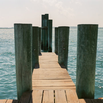 Midday summer sun bakes the boards of a docking pier overlooking the bay