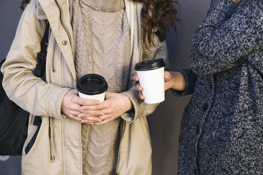Two young women holding coffee to go