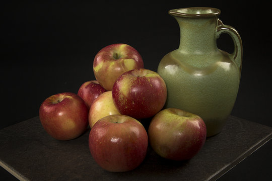 Apples and a Green Vase on a Slate Plate and a Black Background