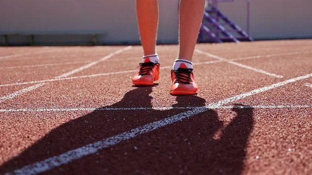 Close detail track runner boy teenager at starting line, slow motion