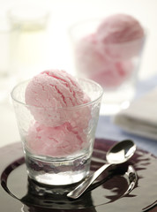 Pink ice cream in glass with silver spoon