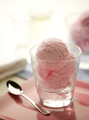 Pink ice cream in glass with silver spoon