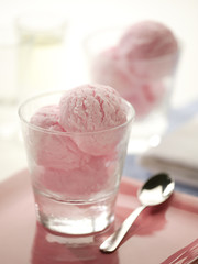 Pink ice cream in glass with silver spoon