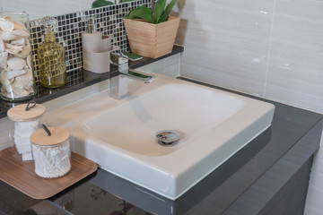 Fototapeta premium Bathroom interior in new luxury home, sink with faucet and decoration set, white washbasin and faucet