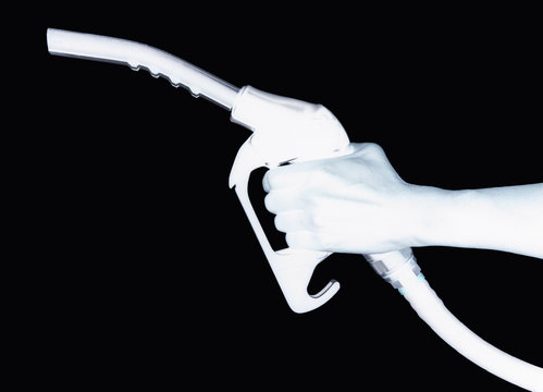 Hand holding petrol pump in silhouette on black background