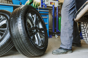 Mechanic changes car wheel in auto repair shop