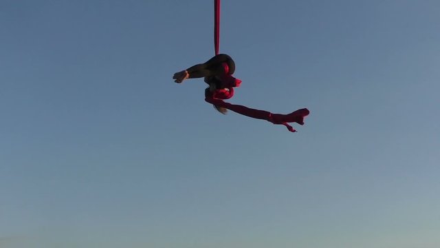 Aerial acrobat shows figures on silk high in the sky.