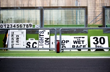 Tuinposter Veel boards voor motorsportracecontrole in de pitlane van het circuit © fabioderby