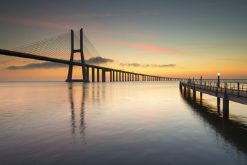 Obraz na płótnie Canvas asco da Gama Bridge and pier over Tagus River in Lisbon, Portugal, just before sunrise