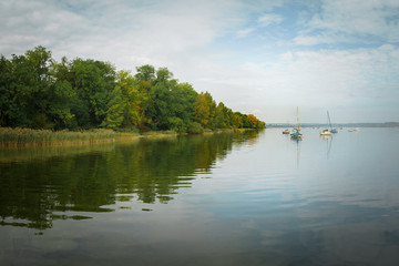 ein See unter einem Herbsthimmel mit gelben Bäumen am Ufer