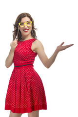 Portrait of Alluring Caucasian Female Holding Yellow Artistic Spectacles Near Eyes. Posing  In Red Polka Dot Dress Against Pure White.Holding Hand in Front.